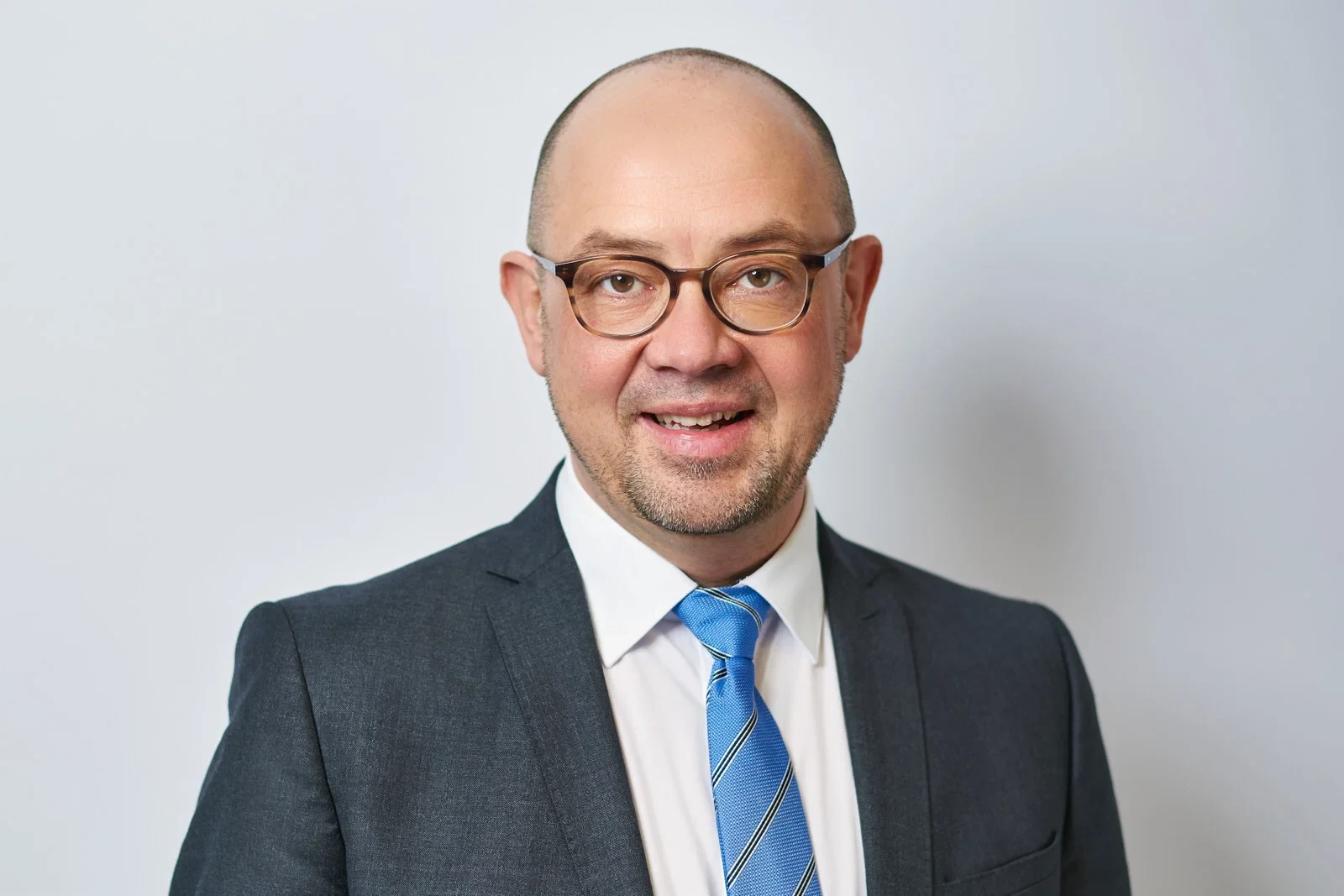 Eine Wissenschaftlerin und ein Wissenschaftler arbeiten hinter einer Glasfassade und mischen Chemikalien mit Großgeräten.