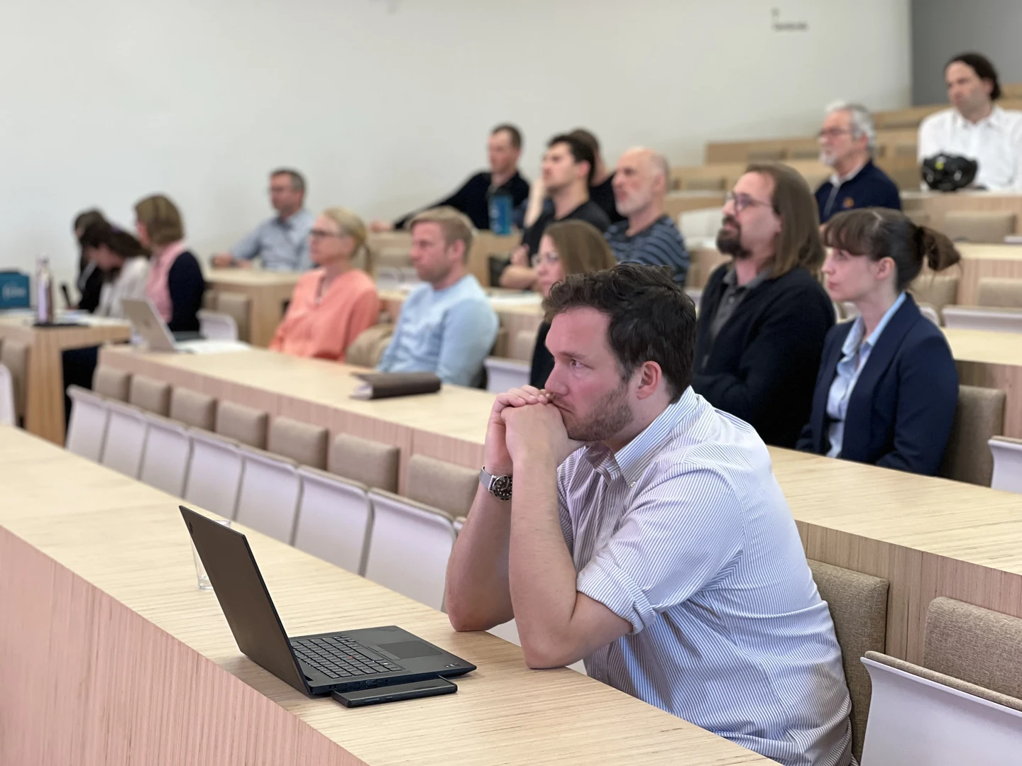 Versammelte Menschen in einem Hörsaal, die sich einen Vortrag anhören.
