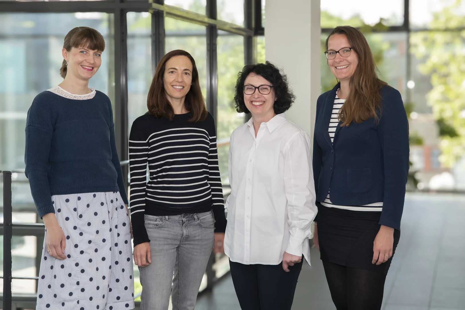 Eine Wissenschaftlerin und ein Wissenschaftler arbeiten hinter einer Glasfassade und mischen Chemikalien mit Großgeräten.