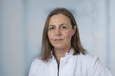 Eine Wissenschaftlerin und ein Wissenschaftler arbeiten hinter einer Glasfassade und mischen Chemikalien mit Großgeräten.