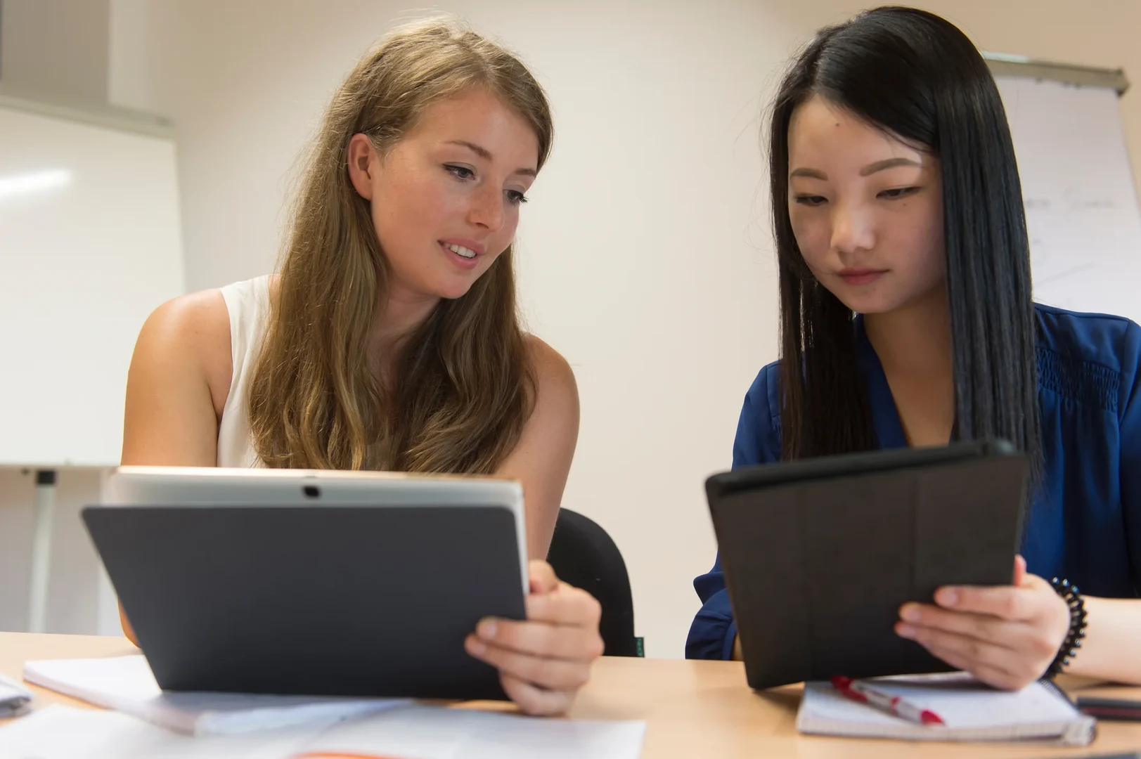 Eine Wissenschaftlerin und ein Wissenschaftler arbeiten hinter einer Glasfassade und mischen Chemikalien mit Großgeräten.