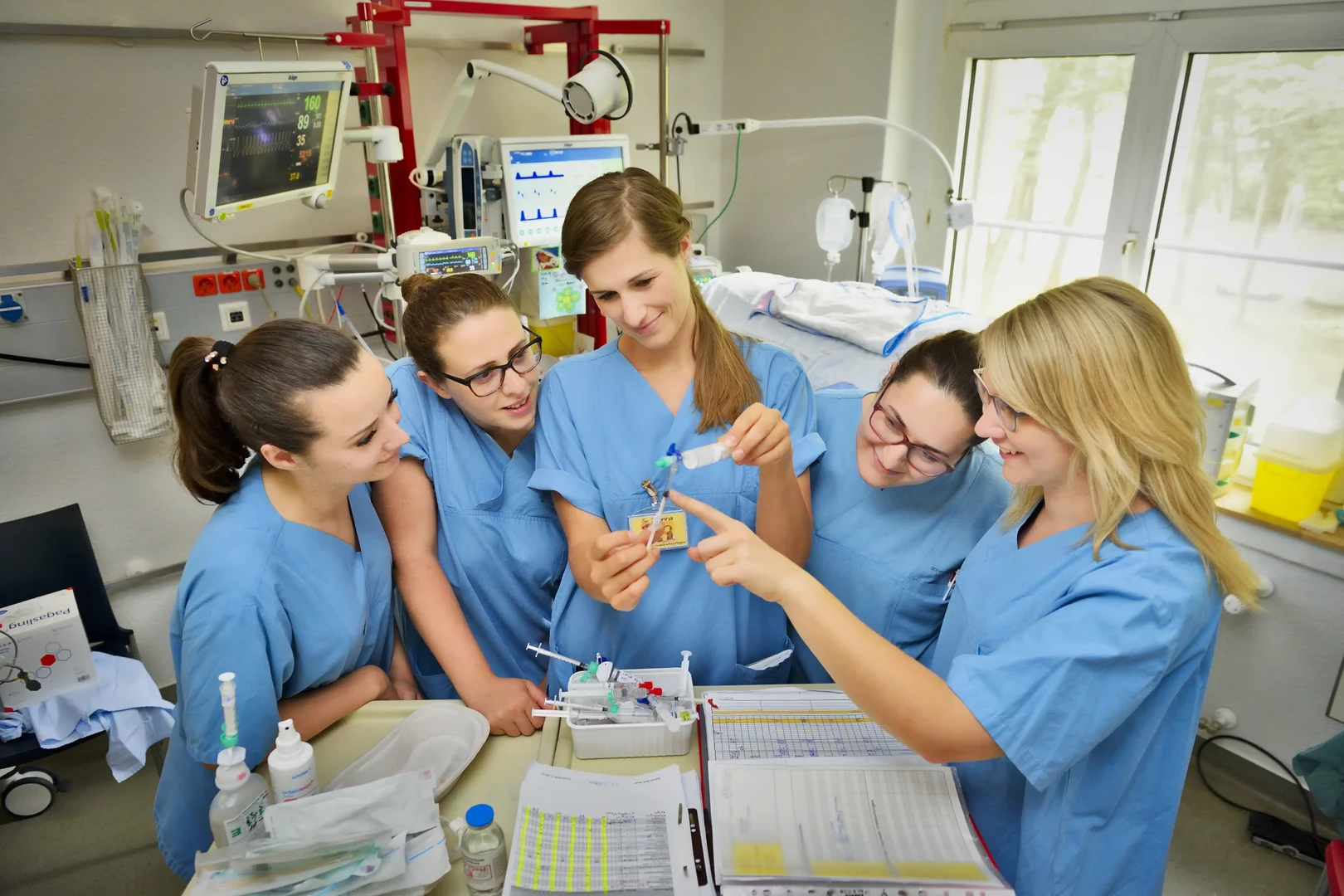 Eine Wissenschaftlerin und ein Wissenschaftler arbeiten hinter einer Glasfassade und mischen Chemikalien mit Großgeräten.