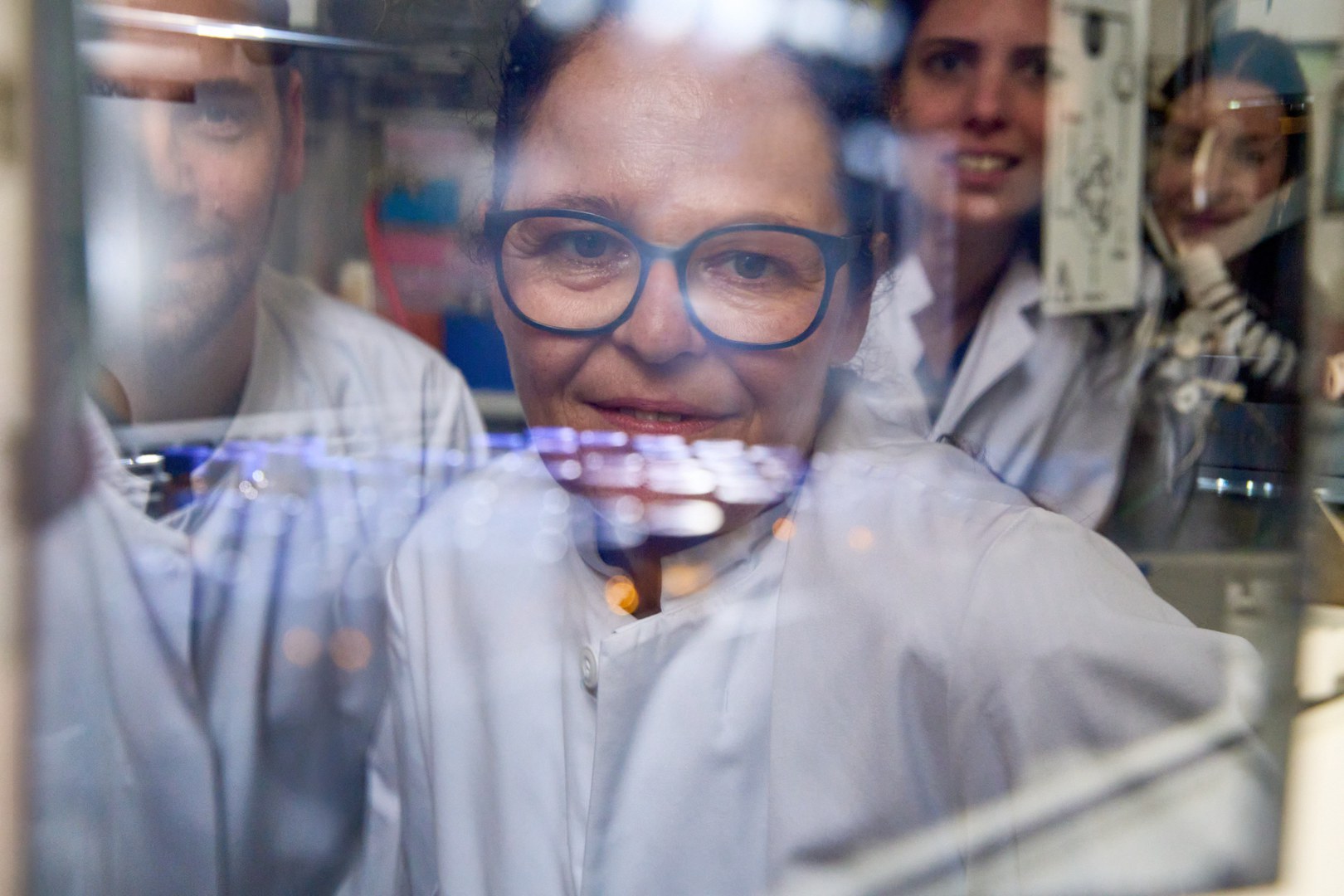 Reflection in the protective screen: - Prof. Dr. Tanja Schneider and her team from the Institute of Pharmaceutical Microbiology.